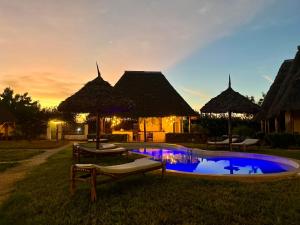 Una piscina con sillas y sombrillas frente a un resort. en MITI Beach Bungalows, en Nungwi