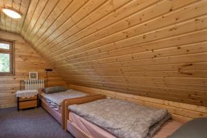 two beds in a room with wooden walls at Mountain Hut Stara Hiša in Kupjak