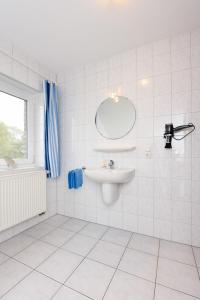 ein weißes Badezimmer mit Waschbecken und Spiegel in der Unterkunft Ferienwohnung Krabbe 2, Bensersiel, mit gemeinschaftlichen Garten in Holtgast