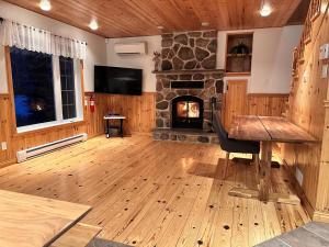 a living room with a stone fireplace and a wooden table at Le Grand Boisé in Saint Zenon