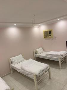 a room with two beds and a air conditioner on the wall at شقة للإيجار شهري اسبوعي يومي تبعد عن الحرم المكي 4 كيلو-قريبة من قطار الحرمين قريبة من محطة باصات رئيسية in Aţ Ţunḑubāwī