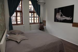 a bedroom with a large bed and two windows at Ferienwohnung Höllenblick in Quedlinburg