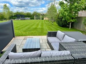 a patio with a couch and a table and a field at Serafina Lodge in Leominster