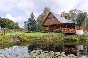 a log cabin with a pond in front of it at Mīļpirtiņa Guguči in Straupe