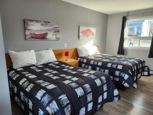a bedroom with two beds and a window at Motel Rimouski in Rimouski