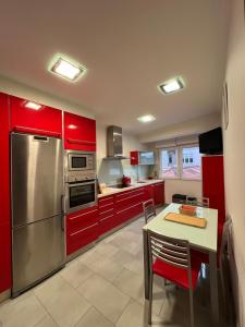 cocina con armarios rojos, mesa y nevera en Marusía apartamento, en Malpica de Bergantiños 37 fotos más