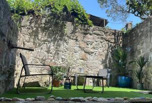 a chair and a table in front of a stone wall at Sol Garden in Porto