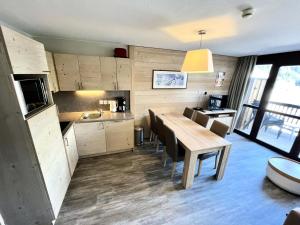 a kitchen and dining room with a wooden table and chairs at Résidence Le Panoramic - Appartement lumineux · Départ et retour skis aux pieds · Piscine · Parking inclus · Spa MAE-0351 in Magland