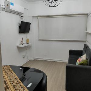 Estilo Mar في مار ديل بلاتا: غرفة معيشة بها أريكة سوداء وشاشة كبيرة