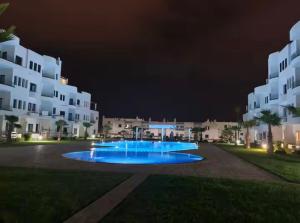 a night view of a pool in front of a building at Amina in Marina Smir
