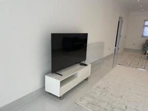Una sala de estar con un televisor de pantalla plana grande en una pared. en 5 Bedroom Modern and Spacious House in London, en Fairlop Station
