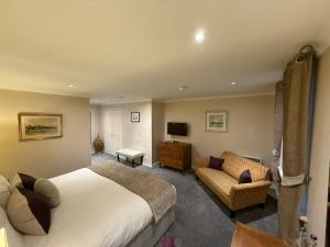 a bedroom with a bed and a couch and a television at The Airds Hotel and Restaurant in Port Appin