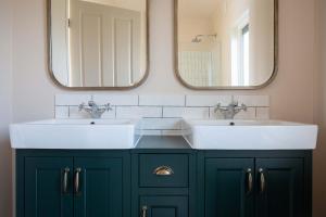 a bathroom with two sinks and two mirrors at Summer Lake in South Cerney +97 photos