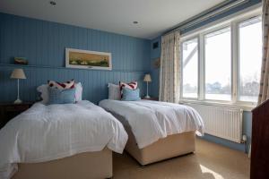 two beds in a room with blue walls and windows at Summer Lake in South Cerney