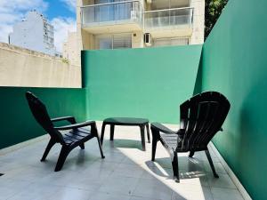2 sillas y una mesa en un balcón con una pared verde en Apartment with Patio, Gym and Pool, en Buenos Aires