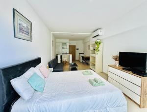 Un dormitorio con una gran cama blanca y un televisor de pantalla plana. en Apartment with Patio, Gym and Pool, en Buenos Aires