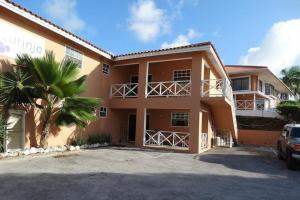 a large house with a palm tree in front of it at Botanical Apartment Central Boho style 2 pools in Willemstad