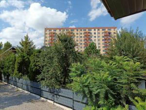 a fence with trees in front of a tall building at pokoje przytulnie jak w domu in Kraków