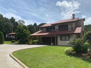 a house with a green lawn in front of it at Sítio das Flores muito espaço e aconchego para reunir família e amigos in Garibaldi