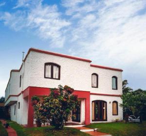 a white and red house with a tree in front of it at Hotel La Casona in La Paloma