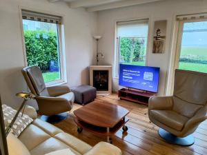 a living room with a couch and a tv at Komfortables Ferienhaus mit Garten, Weitblick und Whirlpool in Tzummarum