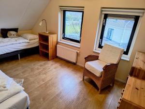 a bedroom with two beds and a chair and window at Komfortables Ferienhaus mit Garten, Weitblick und Whirlpool in Tzummarum