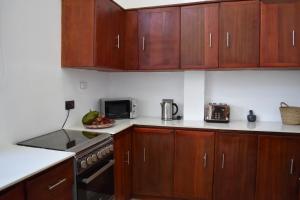 a kitchen with wooden cabinets and a stove top oven at Maneri Villa and Apartments in Zanzibar City
