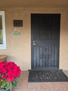 a black door on the side of a house with red flowers at The Gingko House in Pasadena +8 photos