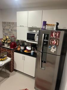 a kitchen with a stainless steel refrigerator and white cabinets at Casa Panorâmica in Angra dos Reis