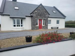uma casa branca com uma porta vermelha e algumas flores em Coastal View Cottage em Mullagh