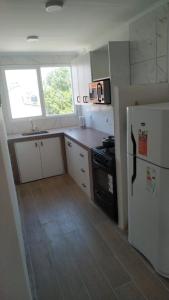 a kitchen with a white refrigerator and a stove at Alquiler Santa Clara del Mar calle Bilbao 4 personas in Santa Clara del Mar +2 photos