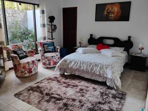 a bedroom with a bed and two chairs and a rug at Mansão Adonai nas Cachoeiras de Penedo in Penedo