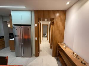 cocina con nevera de acero inoxidable y pasillo en Lindo Apartamento em Cotovelo, en Parnamirim