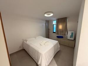 Un dormitorio con una cama blanca y una ventana. en Lindo Apartamento em Cotovelo, en Parnamirim