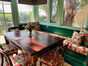 a wooden table and chairs with a vase of flowers at Galway Cottage in Willunga