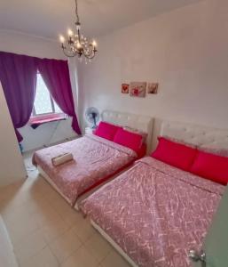 a bedroom with two beds with pink sheets and a chandelier at Muslim Boutique Apartment with Balcony in Tanah Rata +25 photos