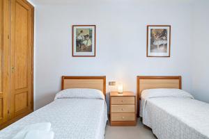 a bedroom with two beds and a night stand with a lamp at Elegante piso en la Romanilla in Roquetas de Mar