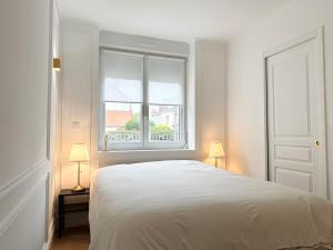 a white bedroom with a bed and a window at L'Opéra - Le Portel in Le Portel