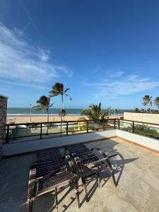 a pair of chairs sitting on a balcony overlooking the beach at AP 103 com Piscina privativa - Flecheiras Residence Summer Plus in Trairi