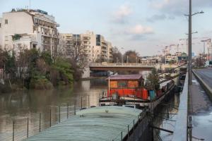 a boat is docked on a river in a city at Issy Citea Access dayuse Room - Work and Day Rest Timeshare -- 2 min tram - Formule Temps Partagé -- Navette ile d'Issy Avenue Paris 92320 espace nuit in Issy-les-Moulineaux