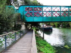 a blue bridge over a river with a boat under it at Issy Citea Access dayuse Room - Work and Day Rest Timeshare -- 2 min tram - Formule Temps Partagé -- Navette ile d'Issy Avenue Paris 92320 espace nuit in Issy-les-Moulineaux