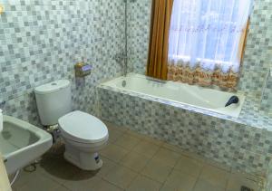 a bathroom with a toilet and a bath tub at Penginapan Syariah Bunga Sonsang in Sungaidaras