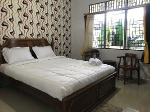 a bedroom with a large bed with white sheets at Penginapan Syariah Bunga Sonsang in Sungaidaras