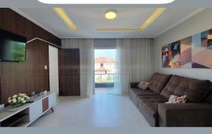 a living room with a couch and a television at Apartamento na Praia do Guaibim in Ponta da Areia
