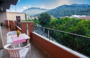 einen Balkon mit einem Tisch, Stühlen und Bergen in der Unterkunft Panos Apartments in Benitses
