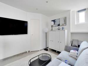Una sala de estar blanca con un sofá y un televisor. en Nice studio 2Pers - Villiers Batignolles, en París