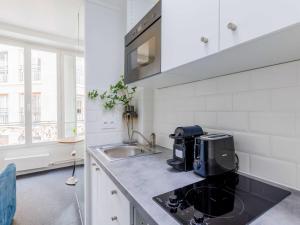 a white kitchen with a sink and a microwave at Charming studio for 2 people - Mobility lease in Paris
