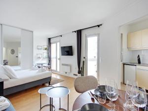 a living room with a bed and a table with wine glasses at Quiet and bright studio - 2P - Rueil Malmaison in Rueil-Malmaison