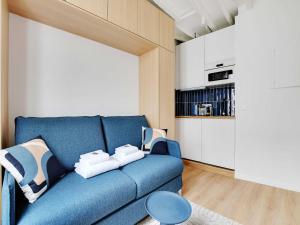a blue couch in a living room with a kitchen at Pleasant studio - 2P - Passy Tour Eiffel in Paris
