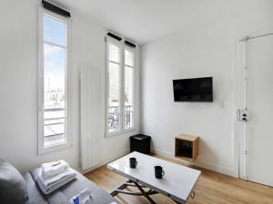 a white living room with a couch and a table at Charming studio - JONQUIERE in Paris